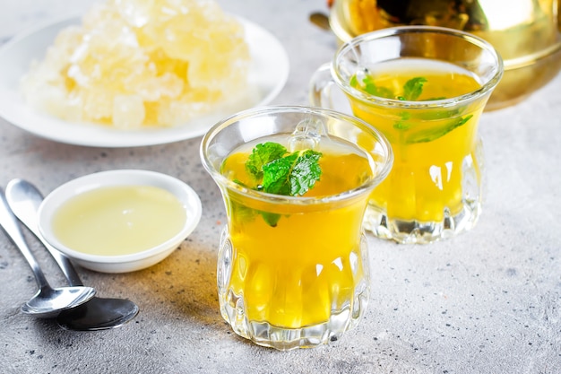 Té oriental con menta, miel y dulces orientales en mesa de hormigón gris. Bebida de Ramadán