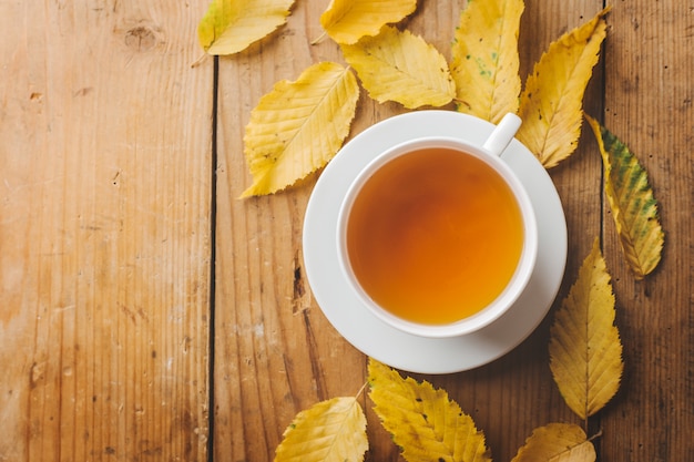 Té de otoño en la mesa de madera con hojas