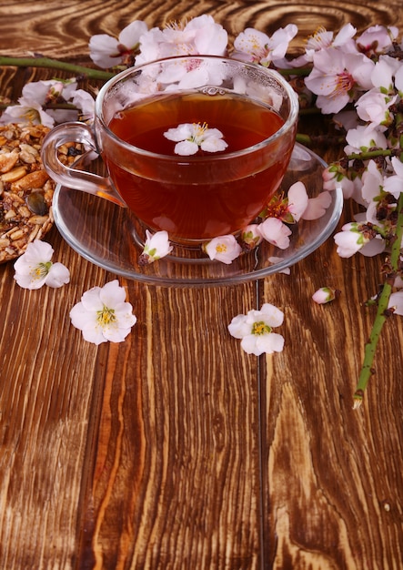 Té y una rama de flores de cerezo en madera