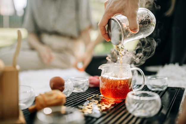 El té rojo elaborado se vierte en una tetera de vidrio El té se vaporiza sobre un fondo del sol