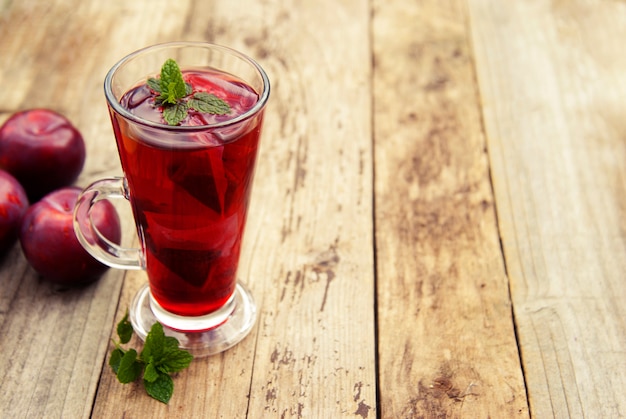 Té rojo de hierbas y frutas en vaso de vidrio y té con ciruelas.