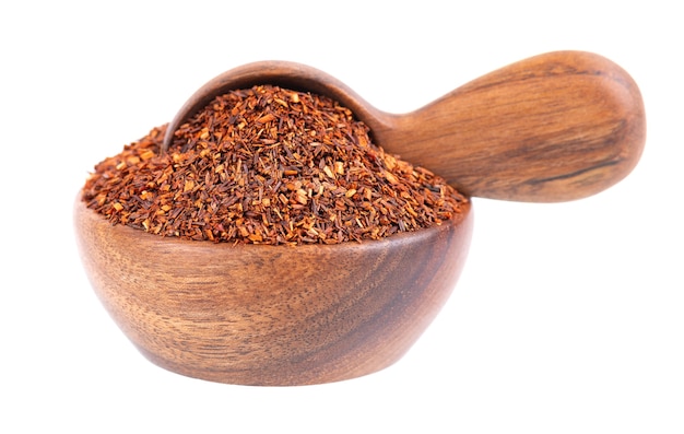 Té rojo Rooibos en cuenco de madera y cuchara aislado sobre fondo blanco orgánico y herbal tradicional