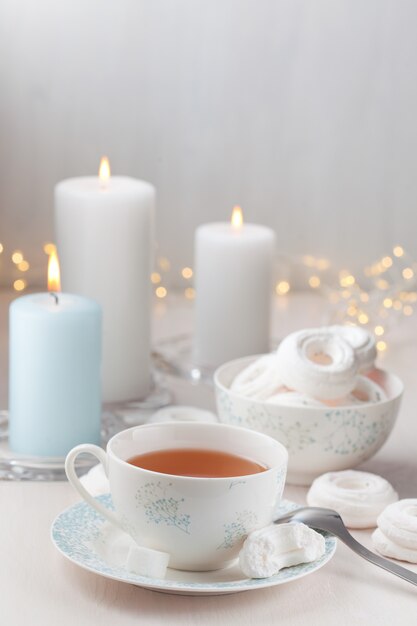 Té romántico y merengues blancos con velas.