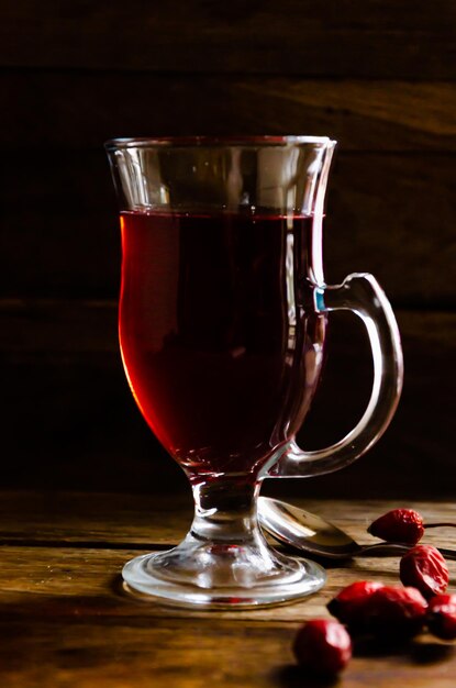 Té de rosa mosqueta en un vaso de vidrio sobre un fondo de madera.