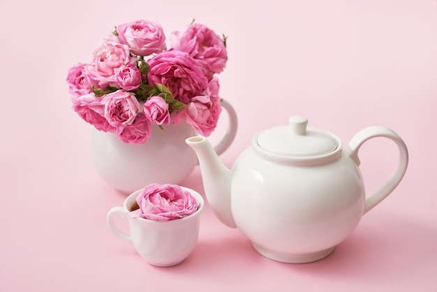 Té con rosas rosadas en la mesa de madera rosa, espacio de copia. Tarjeta de felicitación