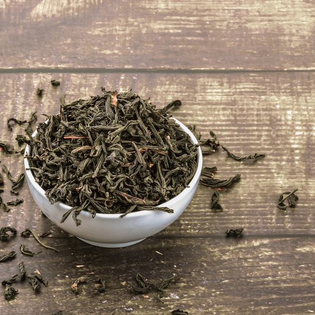 El té seco se vierte en una taza de cerámica sobre una mesa de tablones de madera.