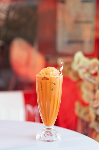 Té tailandés helado en vidrio sobre una mesa blanca en un café vintage