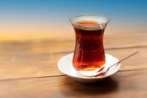 Foto té turco en un vaso en un platillo con una cuchara