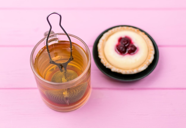 Té en un vaso y un pastel sobre un fondo de madera rosa