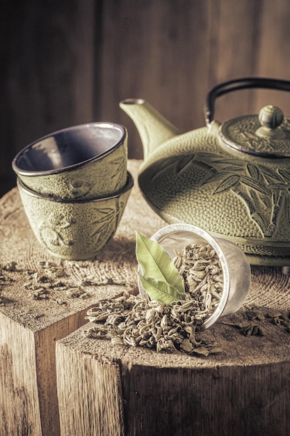 Té verde aromático y frondoso con tetera y taza de hierro