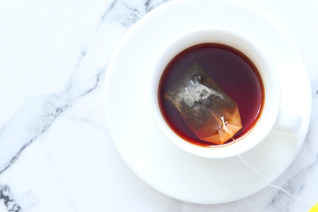 Té verde con bolsita de té sobre fondo de azulejos,