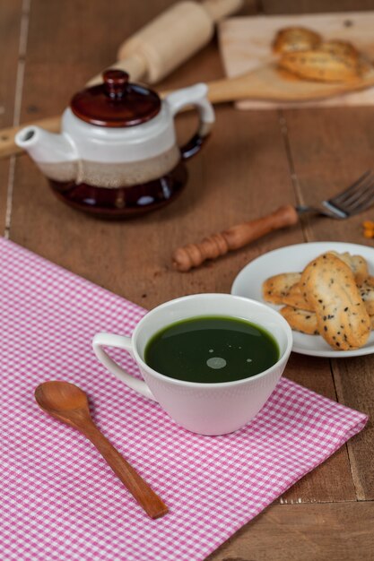 Té verde caliente y fresco en madera con una pequeña galleta dulce hecha en casa con sésamo negro.