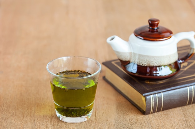 té verde caliente con una pequeña tetera en la mesa de madera.