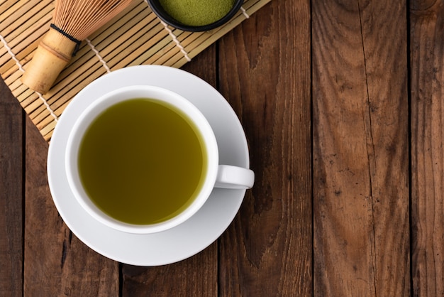 té verde caliente en taza en la madera