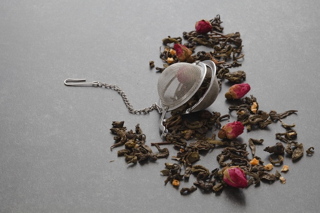 Té verde derramado con una rosa y un colador