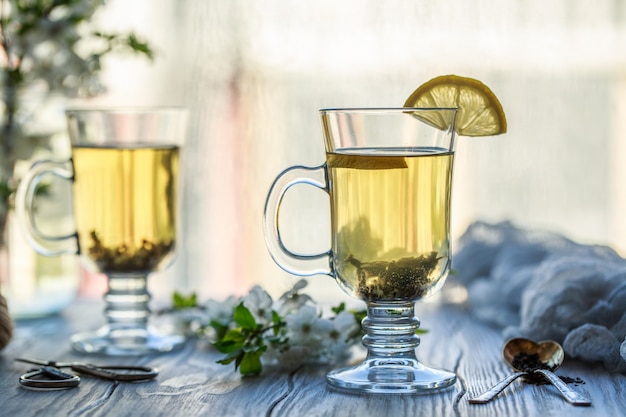 Té verde fresco. Taza de té con hojas de té verde en la mesa de madera. Té con limón