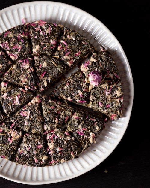 Té verde de hoja prensada con capullo de rosa en el plato