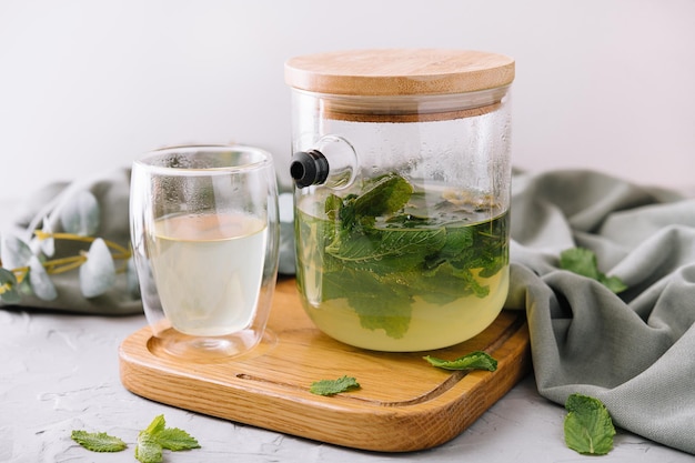 Té verde en una jarra y una taza con menta