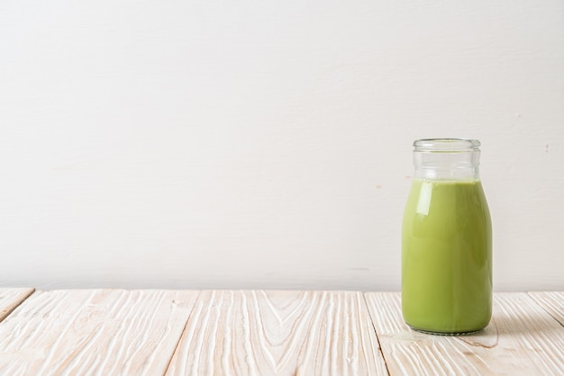 Té verde matcha con leche en botella sobre mesa de madera