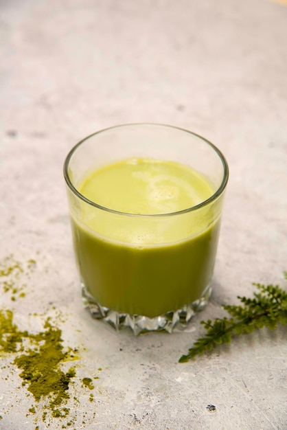 té verde matcha con leche en un vaso sobre un fondo gris