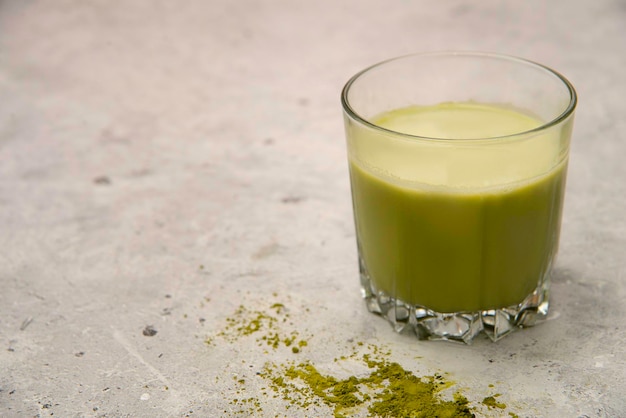 té verde matcha con leche en un vaso sobre un fondo gris