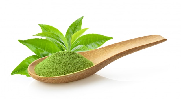 Té verde matcha en polvo en una cuchara de madera con hojas en blanco