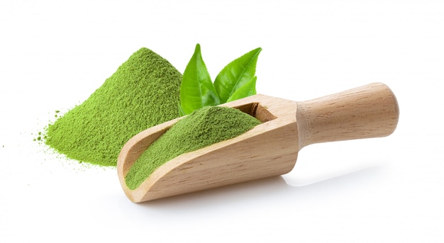 Té verde matcha en polvo en cuchara de madera y hojas en blanco