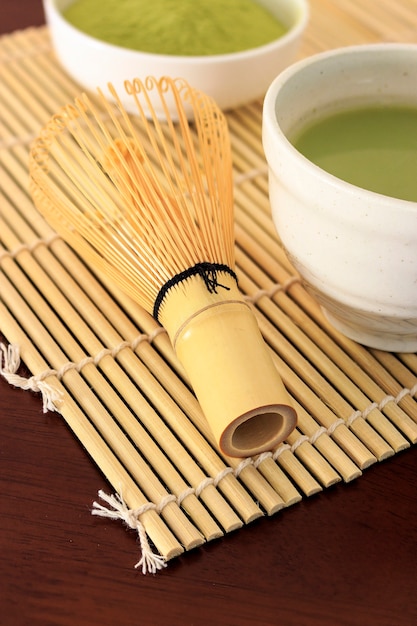 Té verde de Matcha en la tabla de madera con colores calientes de la caída en el foco suave en el fondo.