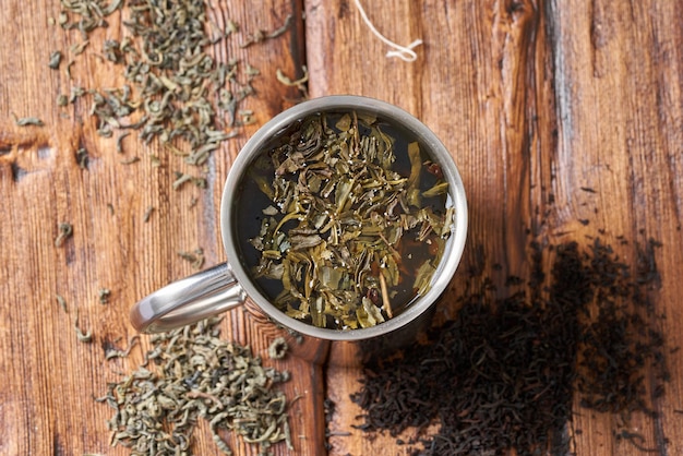 Té verde en una taza de acero inoxidable sobre una mesa de madera antigua