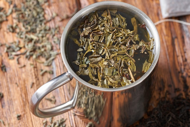 Foto té verde en una taza de acero inoxidable en una vieja mesa de madera