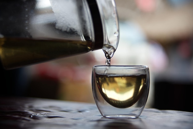 El té se vierte en un vaso transparente con un fondo borroso de burbujas