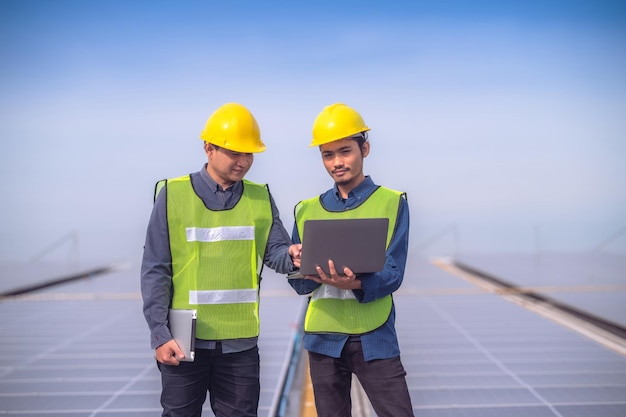 Team Asian Engineer steht auf Dachfabrik und überprüft Solarzellenenergie durch Tablet-Technologie