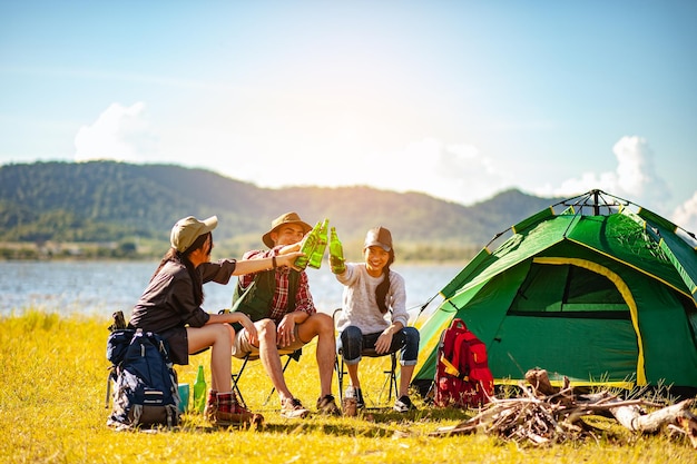 Team asiatischer Bergsteiger-Wanderer sitzt und genießt einen Drink nach einem aufgestellten Outdoor-Zelt in der Waldweg-Herbstsaison. Wandern, Wanderer, Team, Wald, Camping, Aktivitätskonzept.