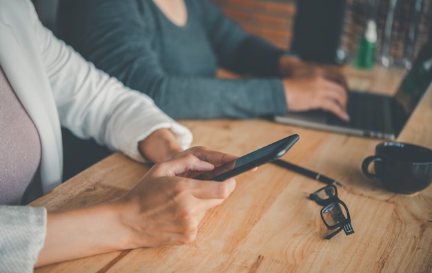 Team-Geschäftsmann-Job. Arbeiten mit Smartphone und Laptop im Großraumbüro. Sitzungsbericht in Bearbeitung