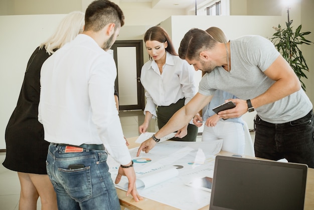 Foto team junger leute, die am tisch mit diagrammen arbeiten