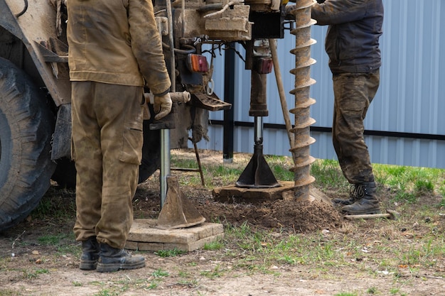 Team von Arbeitern mit Bohrgerät auf dem Auto bohrt artesischen Brunnen für Wasser im Boden Einsetzen von Metallmantelrohren in den Boden Installation der individuellen Trinkwasserversorgung 28. Juni 2022 Russland