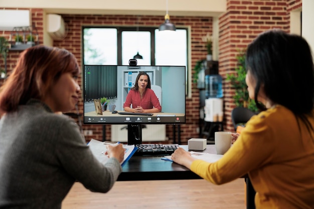 Team von Geschäftsfrauen, die bei der Personalbeschaffung arbeiten und den Lebenslauf mit einem entfernten Bewerber während einer Online-Videoanruf-Konferenz im Büro eines Startup-Unternehmens besprechen. Telefonkonferenz auf dem Bildschirm