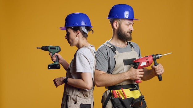 Team von Ingenieuren, die Bohrmaschinen verwenden, um Nägel zu schrauben und an der Bausanierung im Studio zu arbeiten. Bauarbeiter, die mit elektrischer Bohrnagelpistole am industriellen Abbruch arbeiten.