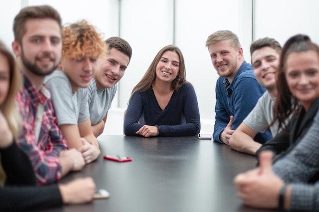 Team von jungen Berufstätigen, die an einem Tisch in einem Konferenzraum sitzen