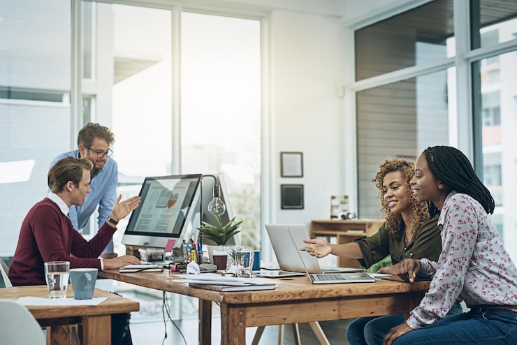 Foto teamarbeit computer und geschäftsleute am schreibtisch im coworking-raum zur diskussion projektplanung oder feedback lensflare vielfalt und mitarbeiter in der designagentur zur zusammenarbeit überprüfung oder bericht