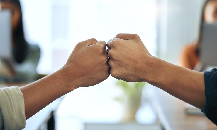 Foto teamwork-kollegen mit fauststoß und an ihrem schreibtisch im büro am arbeitsplatz partnerschaft oder unterstützung der zusammenarbeit oder teambildung und kollegen mit einem händedruck gemeinsam für glückwünsche