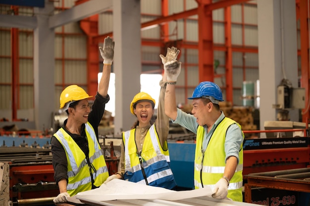 Teamwork-Mitarbeiter Techniker und Ingenieure mit Hardhat oder Helmweste, die die Handkoordination zeigen und die Faust lächeln, um erfolgreich am Arbeitsplatz der Industriefabrik zu arbeiten