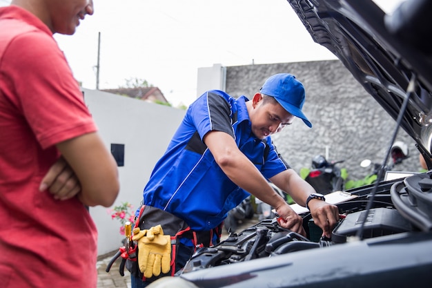 Techinician ayuda al cliente arreglando su auto