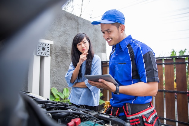 Techinician ayuda al cliente arreglando su auto