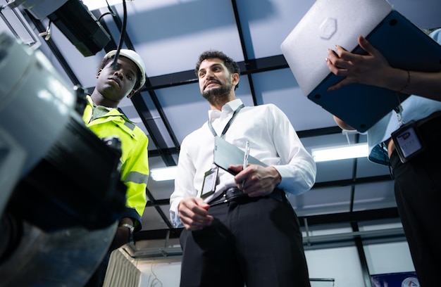 Foto techniker stellen industrielle handroboter geschäftsleuten der fabrikindustrie vor