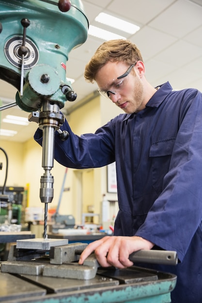 Technikstudent, der großen Bohrer verwendet