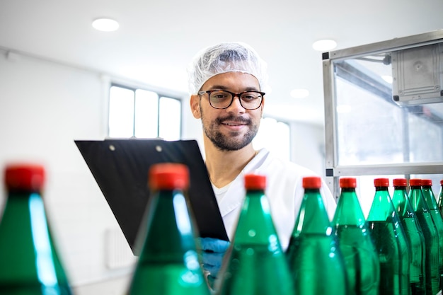 Foto technologe, der die produktion von kohlensäurehaltigem wasser in flaschen in der abfüllfabrik kontrolliert