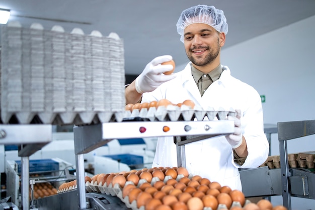 Technologe für sterile Kleidung, Haarnetz und Hygienehandschuhe, der die Qualität von industriell hergestelltem Ei in einer Lebensmittelverarbeitungsanlage oder auf einem Bauernhof überprüft.