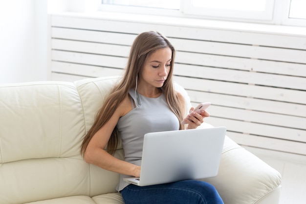 Technologie-, Freiberufler- und Personenkonzept. junge Frau sitzt auf dem weißen Sofa und plaudert im Netbook.