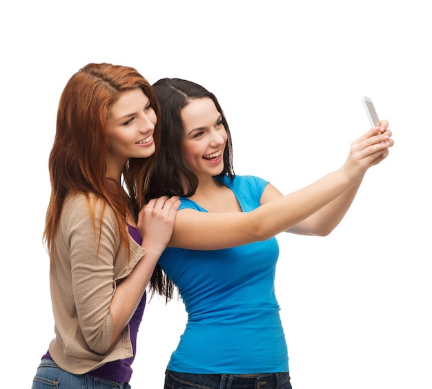 Technologie-, Freundschafts- und Menschenkonzept - zwei lächelnde Teenager, die mit der Smartphone-Kamera fotografieren